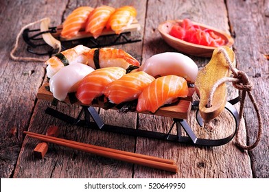 Homemade Sushi With Salmon, Squid And Shrimp On Small Sleigh Christmas Background