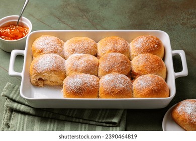 Homemade sweet bread rolls, buns powdered with sugar and filled with apricot jam, in a cooking tray. - Powered by Shutterstock