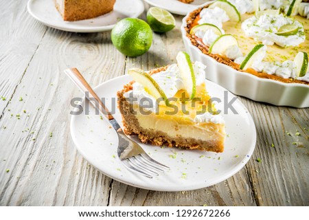 Homemade sweet cake, classic key lime pie with fresh limes, on wooden background copy space