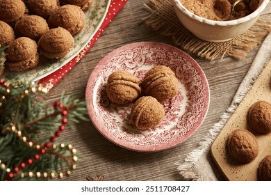 Homemade sweet Christmas cookies in the form of nuts filled with cocoa cream on a red vintage plate with decorated spruce tree branches - Powered by Shutterstock