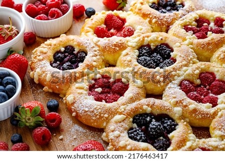 Homemade sweet yeast buns with the addition of berry fruit and butter crumble, sprinkled with powder sugar, close up view
