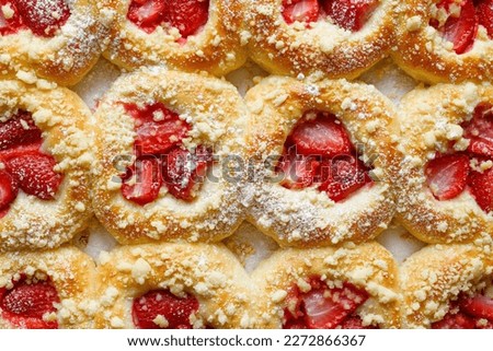 Homemade sweet yeast buns with the addition of strawberries and butter crumble, sprinkled with powdered sugar.