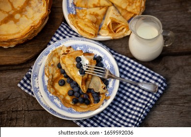 Homemade thin pancakes with blueberries. Pancake on a plate with berry filling. Shrovetide. Breakfast on a wooden table. Baking from batter. Fresh pancakes on a plate.  - Powered by Shutterstock