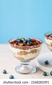 Homemade Tiramisu With Blueberries In Glass Jars. Traditional Unbaked Italian Dessert On Blue Background. Coffee And Mascarpone Cream Cake. Copy Space. Selective Focus.