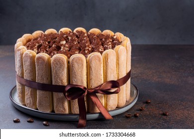 Homemade Tiramisu cake - coffee-flavoured italian dessert, made of savoiardi (ladyfingers), biscuit dipped in coffee and cream of mascarpone cheese, with cocoa. Decorated with bow.