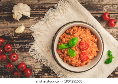 Homemade tomato risotto with fresh basil on a rustic wooden table, top view