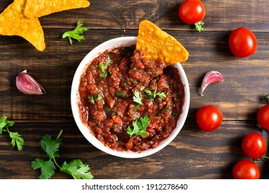 Homemade tomato salsa in bowl over wooden background. Top view, flat lay - Powered by Shutterstock