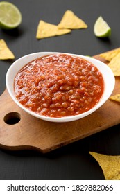 Homemade Tomato Salsa And Nachos On A Rustic Wooden Board On A Black Background, Side View. 