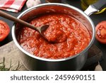 Homemade tomato sauce and spoon in pot on table, closeup