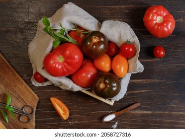 Homemade Tomatoes, Red, Yellow And Black In A Wooden Box, On A Linen Napkin. Overhead, Close-up, Rustic Style.