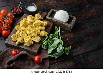 Homemade Tortellini with cheese and basil set, on wooden cutting board, on old dark wooden table background, with copy space for text