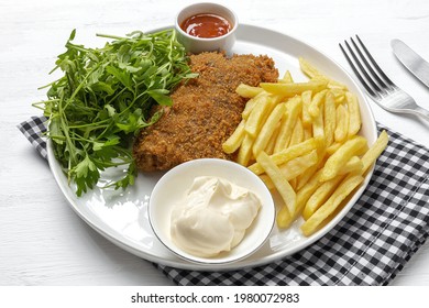 Homemade traditional Milanese veal escalope with french fries, salad, mayonnaise sauce. Italian and Spanish food