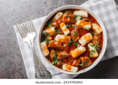 Homemade traditional Polish potato dumplings kopytka served with meat stew close-up in a plate on the table. Horizontal top view from above
