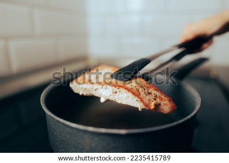 Homemade Tuna Stake Being Flipped Over in a Pan. Person preparing a fish at home searing it on both sides 
