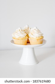 Homemade vanilla cupcakes, with buttercream frosting and sprinkles displayed nicely on pedestals.
