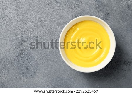 Homemade vanilla custard pudding or lemon curd in a white bowl. top view