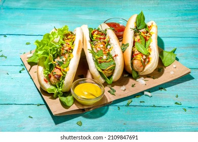 Homemade vegan hotdogs. Hot dog with white meat sausages, fresh vegetables, greens, sauces, over summer sun lighted blue wooden background copy space