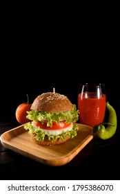 Homemade Vegetarian Cheeseburger And Cocktail Glass Of Red Tomato Juice, Ripe Red Tomato And Green Chili Pepper Close Up On Bamboo Table Isolated On Dark Background