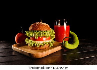 Homemade Vegetarian Cheeseburger And Coctail Glass Of Red Tomato Juice, Ripe Red Tomato And Green Chili Pepper Close Up On Bamboo Table Isolated On Dark Background