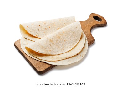 Homemade wheat flour tortilla on wooden cutting board isolated on white background.