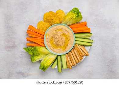 A Homemade White Bean Hummus Surrounded By Cut Vegetables On A Pastel Background  Overhead View