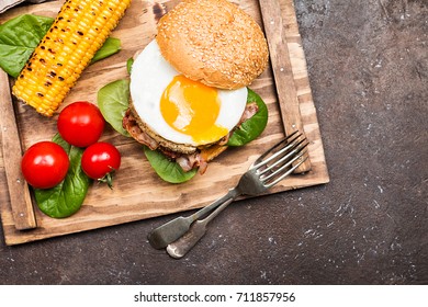 Homemmade Bacon Hamburger with fried Egg, Lettuce and lentil burger with a garnish of corn and tomatoes, top view