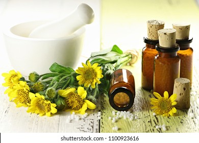 homeopathic arnica pills in brown bottles on wooden background