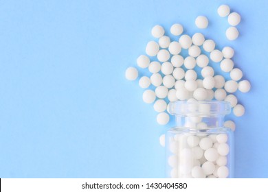 Homeopathic globules and glass bottle on blue background. Alternative Homeopathy medicine herbs, healtcare and pills concept. Flatlay. Top view. copyspace for text.