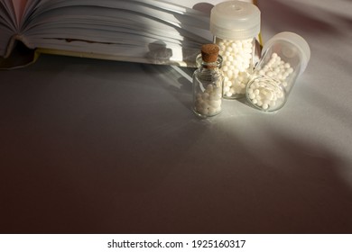 Homeopathic Granules In Storage Flasks. In The Background, A Book On Homeopathic Treatment.