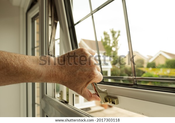 Homeowner seen about to lock a double glazed\
window seen on the ground level of a property. The latch can itself\
be locked to enhance\
security.