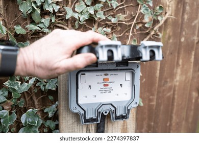 Homeowner showing a fully opened, double gang electrical socket and combined circuit breaker. Note the rubber casket giving a weatherproof seal to these outdoor electrical connections. - Shutterstock ID 2274397837