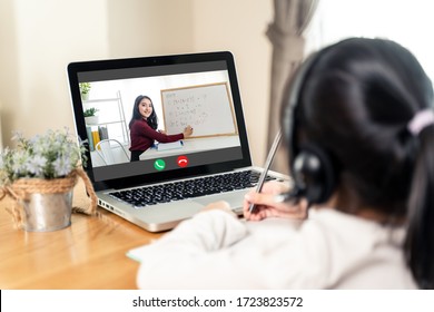 Homeschool Asian Little Young Girl Learning Online Class From School Teacher By Remote Internet Meeting Application Due To Coronavirus Pandemic. Female Teaching Math By Using Headphone And Whiteboard.