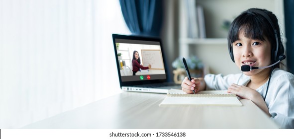 Homeschool Asian Little Young Girl Learning Online Class From School Teacher By Remote Internet Meeting Application Due To Coronavirus Pandemic. Kid Looking Computer Laptop Screen That Woman Teaching.