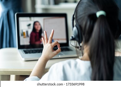 Homeschool Asian Little Young Girl Student Learning Virtual Internet Online Class From School Teacher By Remote Meeting Due To Covid Pandemic. Female Teaching Math By Using Headphone And Whiteboard.