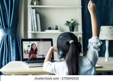 Homeschool Asian little young girl student learning virtual internet online class from school teacher by remote meeting due to covid pandemic. Female teaching math by using headphone and whiteboard. - Shutterstock ID 1733692010
