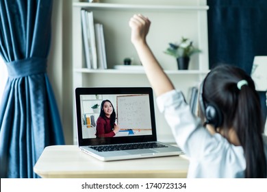 Homeschool Asian little young girl student learning virtual internet online class from school teacher by remote meeting due to covid pandemic. Female teaching math by using headphone and whiteboard. - Shutterstock ID 1740723134
