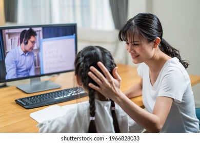 Homeschool Asian Little Young Girl Learning Online Class From School Teacher By Digital Remote Internet Meeting Due To Coronavirus Pandemic. Kid Looking Computer And Writing Note, Sitting With Mother.