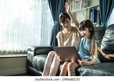 Homeschool Asian Little Young Girl Student Learn Virtual Internet Online Class From School Teacher By Remote Meeting Due To Covid Pandemic. Loving Mother Teach And Support Daughter Use Laptop Computer