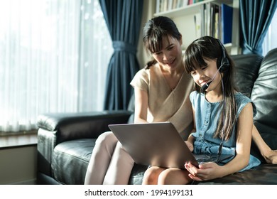 Homeschool Asian Little Young Girl Student Learn Virtual Internet Online Class From School Teacher By Remote Meeting Due To Covid Pandemic. Loving Mother Teach And Support Daughter Use Laptop Computer