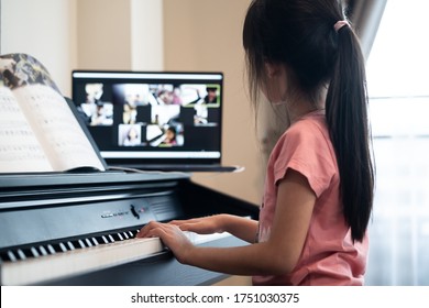 Homeschool Asian Little Young Kid Girl Learning Piano From Computer Connecting To Internet Music Online Class By School Teacher. New Normal Lifestyle And Education, Student Study At Home Concept.