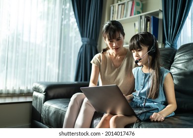 Homeschool Asian Young Girl Learning Online Class With Mother At Home. Little Kid Look To Computer And Study From School Teacher By Digital Remote Internet Meeting Due To Coronavirus Pandemic In House