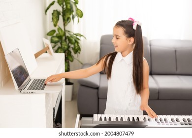 Homeschool Little Young Kid Girl Learning Piano From Computer Connecting To Internet Music Online Class By School Teacher. New Normal Lifestyle And Education, Student Study At Home Concept.