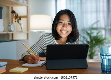 Homeschooling Asian girl doing homework And study online with tablet at the desk night. Portrait of Asia child happiness and smiling confidence looking to camera