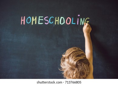 Homeschooling. Child pointing at word Homeschooling on a blackboard.