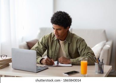 Homeschooling Concept. Black Student Writing In Copybook During Online Conference Or Web Lesson At Home. African American Youth Taking Educational Course, Participating In Webinar