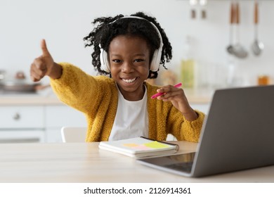 Homeschooling Concept. Portrait Of Happy Black Preteen Girl Study With Laptop At Home, Cheerful Little African American Female Child In Wireless Headphones Showing Thumb Up At Camera And Smiling - Powered by Shutterstock