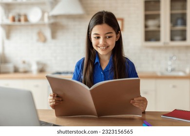 Homeschooling Education. Preteen Arab Girl Reading Text Book Doing School Homework At Home Interior. Middle Eastern Kid Schooler Studying Near Laptop While Sitting At Desk Indoor - Powered by Shutterstock