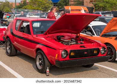 Homestead, Pennsylvania, USA July 21, 2021 A 1977 Red With Black Stripes AMC Gremlin With A Modified Motor And It's Hood Open At A Summer Vintage Car Show