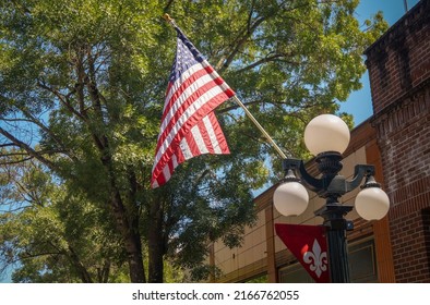 Hometown Pride. An American Flag Hangs On Lamp Post On A Tree Lined Street In A Typical Small Town Main St. USA Scene