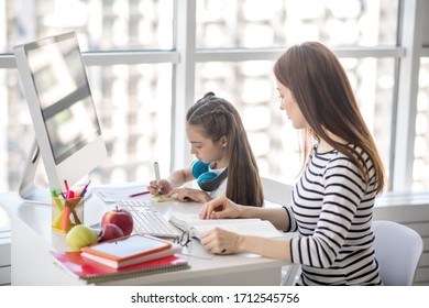 Homework. Dark-haired girl and her tutor sitting at the table doing homework - Shutterstock ID 1712545756
